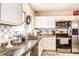Well-lit kitchen features white cabinets, stainless steel appliances, and decorative backsplash at 4406 Carrollton Ave, Indianapolis, IN 46205
