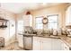 Bright kitchen featuring white cabinetry, stainless steel dishwasher, and a view to the entry door at 4406 Carrollton Ave, Indianapolis, IN 46205