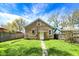 Back view of home with level lawn, mature trees, and gravel walkway at 4623 Evanston Ave, Indianapolis, IN 46205