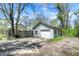 Detached garage with a white door and siding, situated in a backyard with a partial fence and gravel driveway at 4623 Evanston Ave, Indianapolis, IN 46205