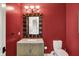 Stylish powder room with decorative mirror, granite countertop, and a modern toilet against a red wall at 4726 Ellery Ln, Indianapolis, IN 46250