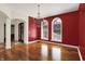 Elegant dining room featuring a striking red accent wall, hardwood floors, and a decorative chandelier at 4726 Ellery Ln, Indianapolis, IN 46250