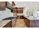 Well-lit kitchen with stone backsplash, stainless appliances, granite counters, and dark wood cabinets at 4726 Ellery Ln, Indianapolis, IN 46250