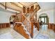 Spacious foyer with a grand wooden staircase and views into dining and living spaces at 5001 Woodrose Ln, Anderson, IN 46011