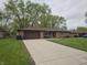 This brick home features a long driveway leading up to a garage and a manicured lawn at 5107 Saddle Ln, Anderson, IN 46013