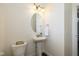 Cozy powder room with a pedestal sink, decorative mirror, and convenient access to the staircase at 5141 S Cobblestone Dr, Zionsville, IN 46077
