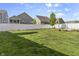 Expansive backyard with a lush green lawn, bordered by a white fence and neighboring houses at 5465 Tanglewood Ln, Whitestown, IN 46075