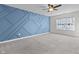 A bedroom with a blue accent wall, ceiling fan, carpeted floors, and a window providing natural light at 5465 Tanglewood Ln, Whitestown, IN 46075