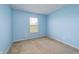 A simple bedroom with light blue walls features a carpeted floor and a window with blinds for natural light at 6209 Amber Valley Ln, Indianapolis, IN 46237