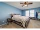 Spacious primary bedroom features a rustic wood bed frame, two windows, and a ceiling fan at 6209 Amber Valley Ln, Indianapolis, IN 46237