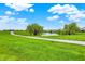 Lush green space with a winding path leading to a pond surrounded by mature trees and neighborhood homes at 6241 Colonial Dr, Whitestown, IN 46075