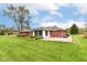 Wide shot of the backyard and home, featuring a lawn, patio, and manicured shrubs at 8606 N Washington Blvd, Indianapolis, IN 46240