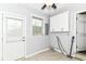 Laundry room with tile floors, grey walls, window, cabinets, utility hookups, and access to the backyard at 8606 N Washington Blvd, Indianapolis, IN 46240