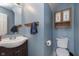 Powder room features blue walls, a vanity, and a cabinet with decorative floral art at 8709 Orchard Grove Ln, Camby, IN 46113