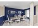 Elegant dining room featuring a wooden table, white chairs, and a stylish dark blue accent wall at 8709 Orchard Grove Ln, Camby, IN 46113