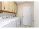 Bright laundry room with cabinets over washer and dryer next to door at 8709 Orchard Grove Ln, Camby, IN 46113
