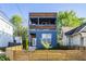 Charming three-story home with a striking blue facade, wood accents, and a welcoming fenced front yard at 1226 Cottage Ave, Indianapolis, IN 46203