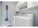 Functional laundry room with modern white washer and dryer, cabinet storage, and cleaning supplies at 13363 Lantern Rd, Fishers, IN 46038