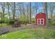 Red storage shed with white doors, surrounded by trees and landscaping at 13363 Lantern Rd, Fishers, IN 46038
