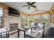 Inviting sunroom with a stone fireplace, comfortable seating, mounted TV, and views of the lush backyard at 13363 Lantern Rd, Fishers, IN 46038