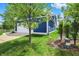 View of the home's blue siding, driveway, tree and part of the manicured lawn on a sunny day at 1404 Rosebank Dr, Westfield, IN 46074