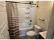 Renovated bathroom with white tub, vanity and neutral striped shower curtain at 1405 S Ribble Ave, Muncie, IN 47302