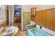 A vintage bathroom features a blue bathtub, sink, and toilet with retro wood paneling and green tiling at 1529 E Gimber St, Indianapolis, IN 46203