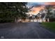 Stunning exterior view of a large home with a three-car garage and a spacious driveway during a vibrant sunset at 15617 Westfield Blvd, Carmel, IN 46033