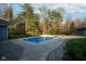 Backyard of home with an in-ground pool with surrounding concrete and lush landscaping with a wooded backdrop at 15617 Westfield Blvd, Carmel, IN 46033