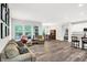 Open-concept living room with hardwood floors, large windows and view into kitchen and dining area at 16693 Churning Way, Noblesville, IN 46060