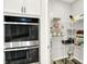 Organized pantry featuring wire shelving, a double oven, white cabinets, and storage for kitchen essentials at 16693 Churning Way, Noblesville, IN 46060