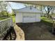 View of a detached single-car garage with a white exterior and classic detailing, accessible via a cracked driveway at 1716 Arlene Dr, Indianapolis, IN 46219