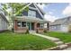 A cozy two-story home showcases a welcoming front porch with a green door at 1852 Singleton St, Indianapolis, IN 46203