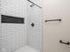 Modern shower features white subway tile, black hardware, and convenient built-in shelving at 1852 Singleton St, Indianapolis, IN 46203