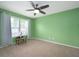 Bright green bedroom with a ceiling fan, carpet, and a small decorative table at 1909 Orange St, Indianapolis, IN 46203