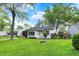 Cozy one-story home with a lush green lawn, mature trees, and tidy landscaping on a sunny day at 2307 Magnolia Pl, Indianapolis, IN 46219