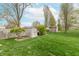 A fenced backyard with two storage sheds, manicured bushes and lawn, and mature trees at 3003 Foxpointe Dr, Columbus, IN 47203