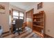 Bright home office with wood floors, desk by a window, and closet with built-in bookshelf at 3003 Foxpointe Dr, Columbus, IN 47203