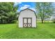 Well-maintained storage shed with double doors, set in a spacious green yard, offering ample outdoor storage at 3154 E German E Rd, Shelbyville, IN 46176