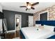 Cozy bedroom featuring a brick accent wall, ensuite bath, ceiling fan, and hardwood floors at 319 S Randolph St, Indianapolis, IN 46201