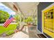 Inviting front porch featuring a swing, American flag, a yellow front door, and views of the green lawn at 3405 W 8Th Street Rd, Anderson, IN 46011