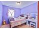 A cozy purple bedroom with a decorative window curtain, guitar, and a bright vanity at 3535 Ivory Way, Indianapolis, IN 46227