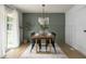 Dining room area with elegant lighting fixture, stylish decor, wood flooring, and green accent wall at 3864 Esquire Ct, Indianapolis, IN 46226