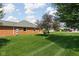 View of a spacious, well-maintained backyard with a brick home exterior and mature trees at 389 Vinewood N Dr, Brownsburg, IN 46112