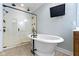 A luxurious bathroom boasts a soaking tub, a glass shower, and a mounted TV for a relaxing experience at 3965 Andretti Dr, Zionsville, IN 46077