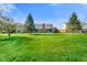 Large, grassy backyard showing brick home with sunroom, mature trees, and clear sky at 4316 Moss Ridge Cir, Indianapolis, IN 46237