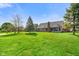 Spacious backyard with lush green grass, mature trees, and brick house with sunroom at 4316 Moss Ridge Cir, Indianapolis, IN 46237