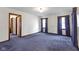 Spacious living room featuring blue carpet, natural light from two windows, and an open doorway at 46 N Kitley Ave, Indianapolis, IN 46219