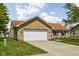 View of brick home with two-car garage, concrete driveway, and lawn with tree at 504 Countryside Dr, Lebanon, IN 46052
