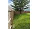 Spacious backyard with wood fence, lush green grass, and mature shade tree, perfect for outdoor enjoyment at 5327 Traditions Dr, Indianapolis, IN 46235